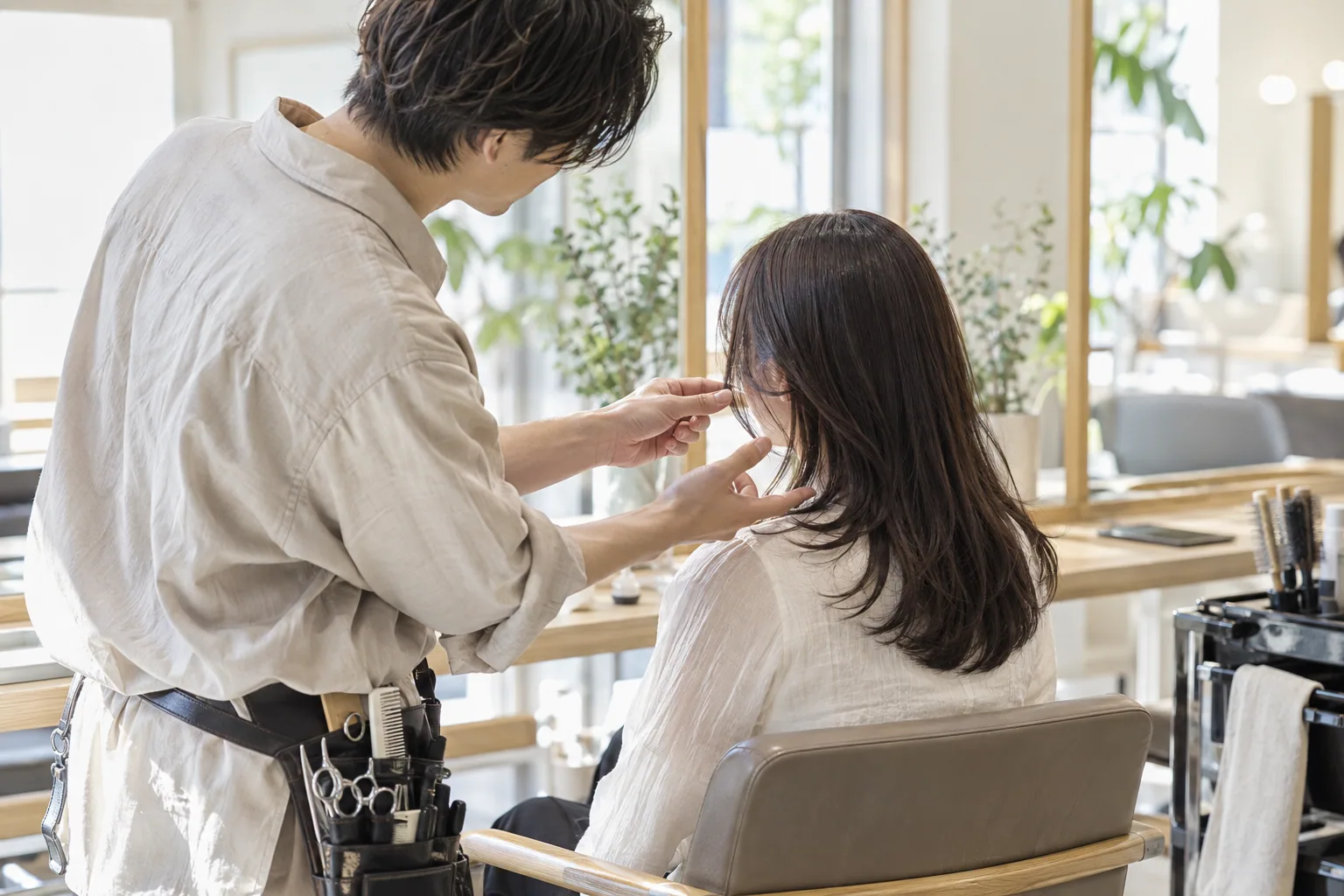 鏡の前で顔まわりの長さを相談するスタイリストとお客さまのイメージ